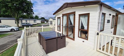 a small white tiny house with a porch at KMH Caravans at Flamingo Land in Kirby Misperton