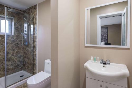 a bathroom with a sink and a toilet and a mirror at Super 8 by Wyndham Niagara Falls ON in Niagara Falls