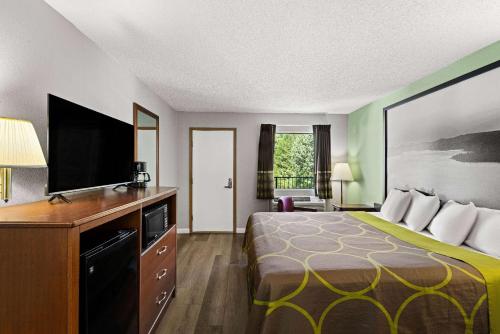 a hotel room with a bed and a flat screen tv at Super 8 by Wyndham Branson - Shepherd of the Hills Exwy in Branson