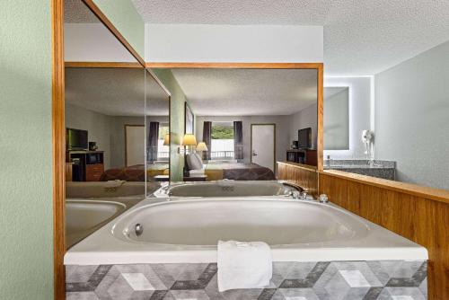 Super 8 by Wyndham Branson - Shepherd of the Hills Exwy في برانسون: حوض استحمام كبير في الحمام مع مرآة