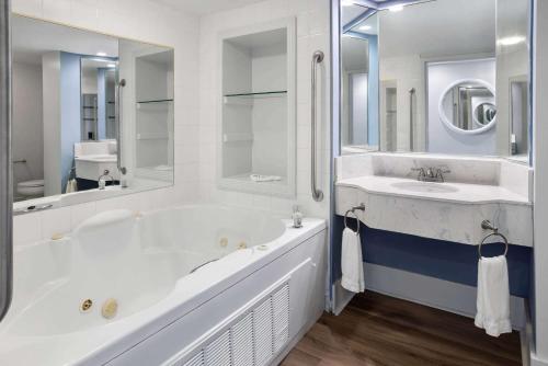 ein weißes Badezimmer mit einer Badewanne und einem Waschbecken in der Unterkunft WaterView Casino & Hotel, Trademark Collection by Wyndham in Vicksburg