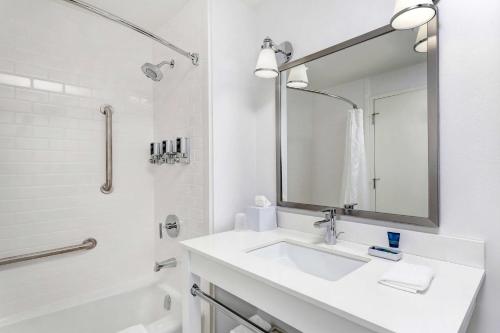 ein weißes Badezimmer mit einem Waschbecken und einem Spiegel in der Unterkunft Wyndham Fallsview Hotel in Niagara Falls