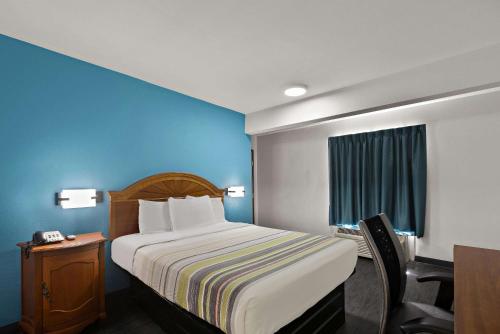 a hotel room with a bed and a desk with a chair at Rodeway Inn Commerce in Commerce