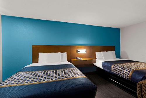 a hotel room with two beds and a blue wall at Rodeway Inn Commerce in Commerce