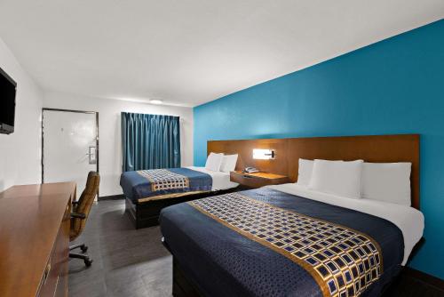 Habitación de hotel con 2 camas y pared azul en Rodeway Inn, en Commerce