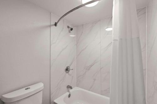 a white bathroom with a shower and a toilet at Rodeway Inn Commerce in Commerce