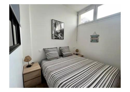 a bedroom with a bed with striped sheets and a window at Appartement Louise in Le Havre