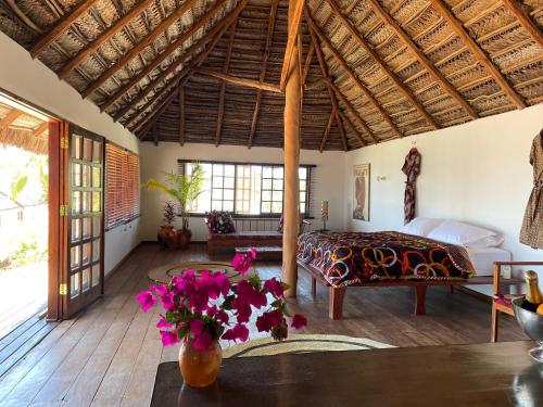 a bedroom with a bed and a table with flowers at umbila:Barra in Inhambane
