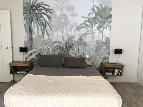 um quarto com uma cama com um mural de palmeiras em Maison de village avec 2 jardins em Pernes-les-Fontaines