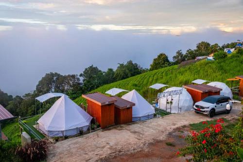 Mon Jam的住宿－อาฉ่างแคมป์ Achang Camp，山丘上一群帐篷,有车
