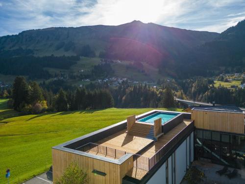 a house with a swimming pool and a mountain at Genuss- & Aktivhotel Sonnenburg in Riezlern
