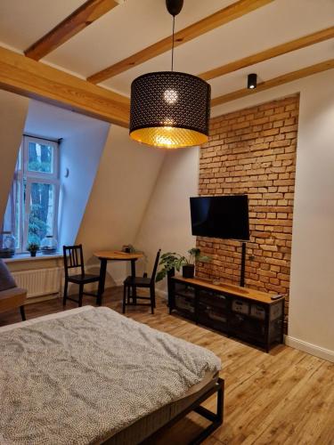 a living room with a brick wall and a flat screen tv at Casa Mama c entrum in Poznań