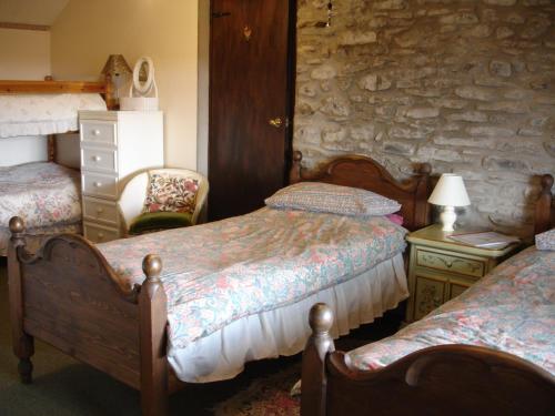 a bedroom with two beds and a stone wall at Five Saints Farmhouse B&B in Pumpsaint