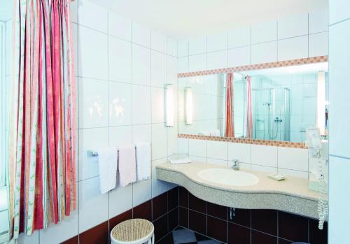 ein Bad mit einem Waschbecken und einem Spiegel in der Unterkunft Pension Schiessling in Anif