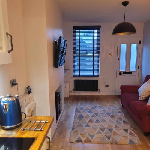 a living room with a red couch and a fireplace at LITTLE HAVEN 1 Bedroom House sought after area in Topsham
