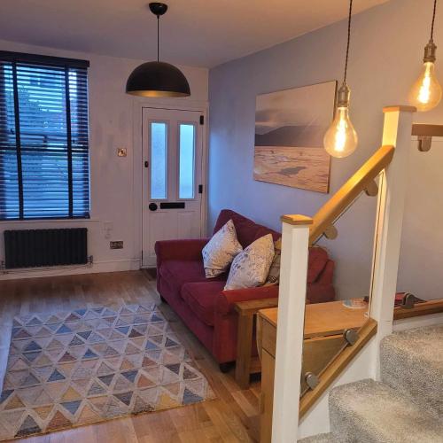 a living room with a red couch and a staircase at LITTLE HAVEN 1 Bedroom House sought after area in Topsham