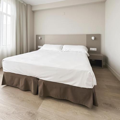 a large white bed in a white bedroom at Hotel El Águila in Utebo