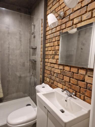a bathroom with a white sink and a brick wall at Casa Mama c entrum in Poznań
