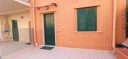 ein Backsteingebäude mit grünen Türen und einem Zaun in der Unterkunft B&B af in Massafra
