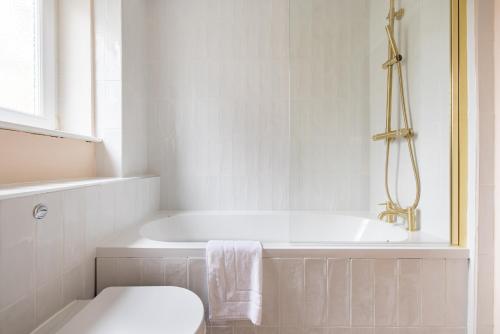 a white bathroom with a tub and a toilet at The Walworth Hideout - Elegant 2BDR Flat in London