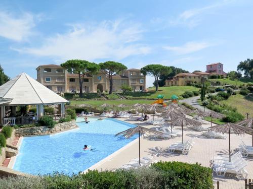 a pool with umbrellas and people in a resort at Apartment Il Felciaione-18 by Interhome in Riparbella