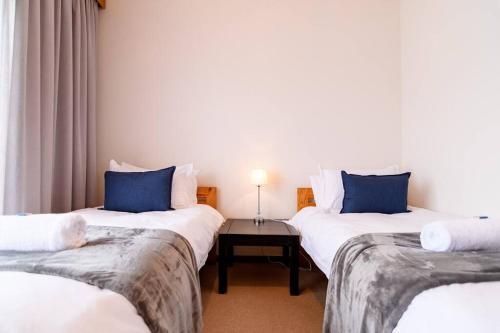 een kamer met 2 bedden met blauwe kussens en een tafel bij Ocean Wave No.1 Self Catering in Swakopmund