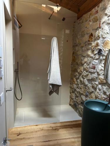 a glass shower in a bathroom with a stone wall at Nuovo B&B Colline San Benedetto in Marostica