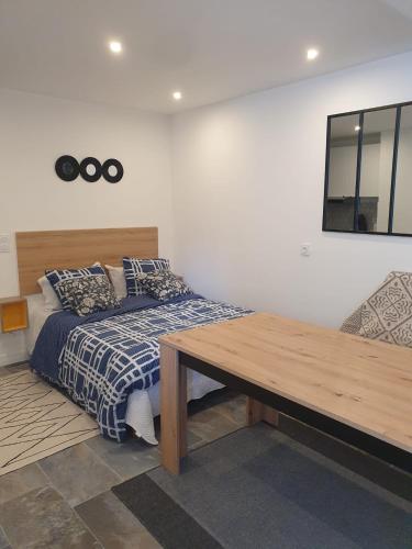 Schlafzimmer mit einem Bett und einem Holztisch in der Unterkunft Beau studio moderne proche de CDG/Paris/Parc d'Expo in Aulnay-sous-Bois
