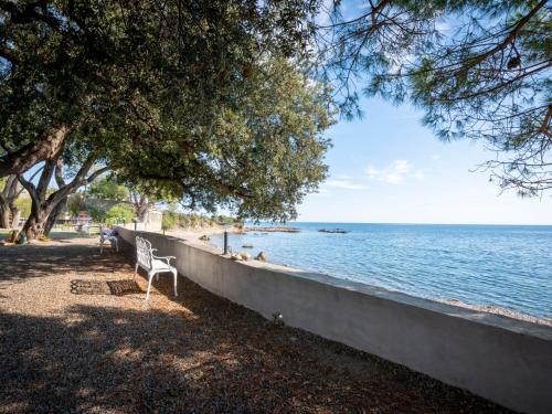 a white chair sitting next to a wall next to the water at Holiday Home Ciriola by Interhome in Sari Solenzara