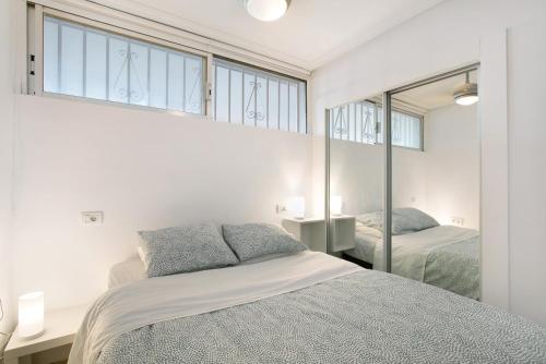 a white bedroom with two beds and a mirror at Apartment at 30 mts from sea in Playa de las Americas