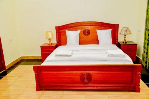 Freedom Homes Kigali في كيغالي: سرير خشبي كبير في غرفة نوم مع مواقف ليلتين