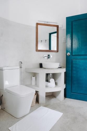 a bathroom with a toilet and a sink and a blue door at Lighthouse Ahangama in Ahangama