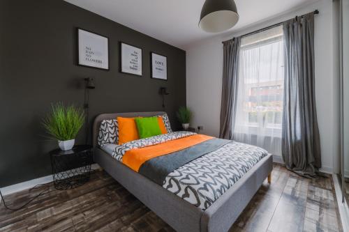 a bedroom with a bed with colorful pillows and a window at SmartSleep Apartments in Glasgow