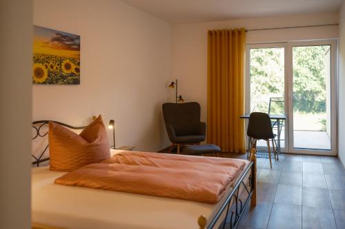 a bedroom with a bed and a chair and a window at Pension Haus am Picho in Arnsdorf