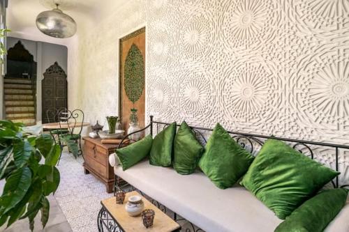 a living room with a white couch with green pillows at Riad des Mile Nuits in Marrakesh