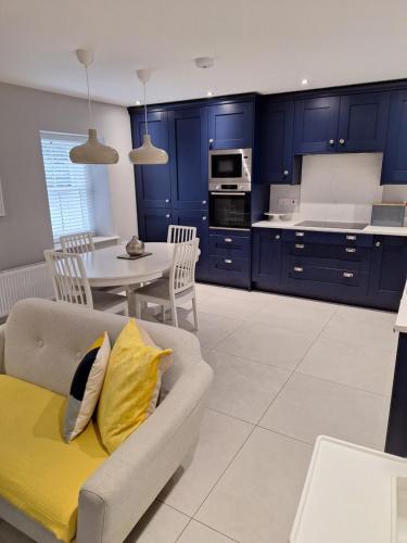uma cozinha com armários azuis, um sofá e uma mesa em Ryan's Cottage em Rostrevor