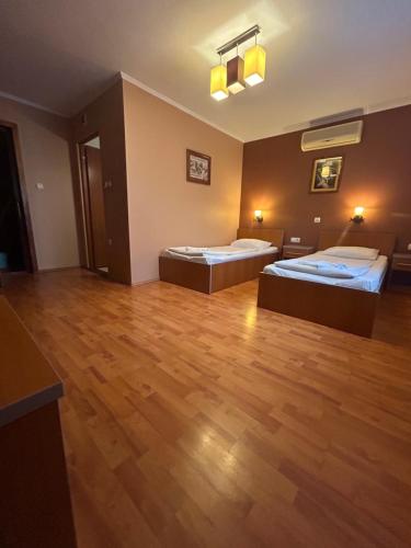 two beds in a large room with wooden floors at Capone in Satu Mare
