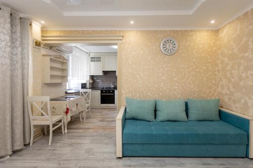 a living room with a blue couch and a kitchen at Stylish apartment in Sumy