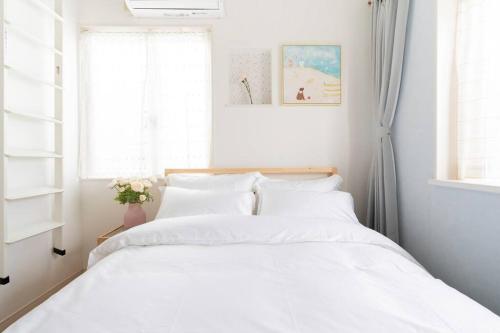a bedroom with a bed with white sheets and a window at Kishisato Japanese House QB-1 in Osaka