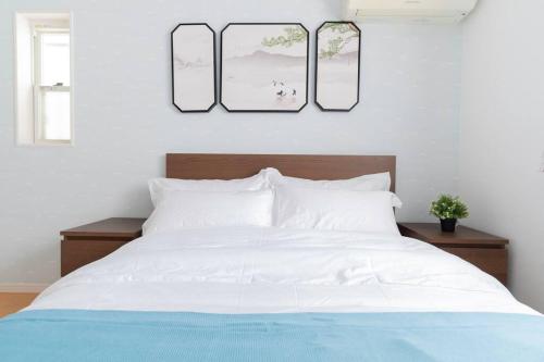 a bedroom with a white bed with two pictures on the wall at Kishisato Japanese House QB-1 in Osaka