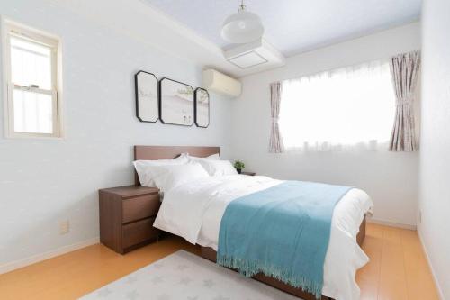 a white bedroom with a bed and a window at Kishisato Japanese House QB-1 in Osaka