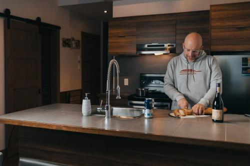 a man standing in a kitchen preparing food at Lake Resort Suite: Views & Amenities in Lac-Superieur