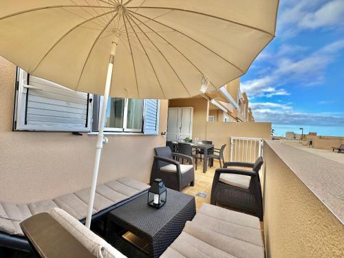 eine Terrasse mit Stühlen und einem Sonnenschirm auf dem Balkon in der Unterkunft Apartamento Vista Faro in Poris de Abona