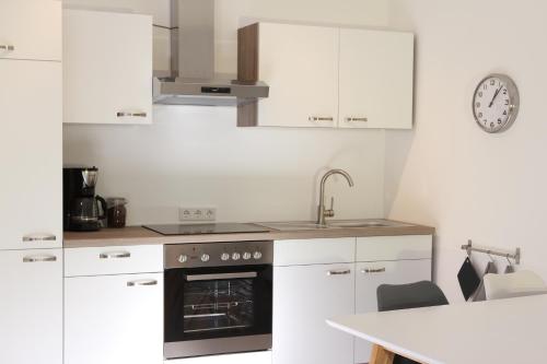 a kitchen with white cabinets and a sink and an oven at Ferienwohnung 1 ANNA IFF in Würzburg