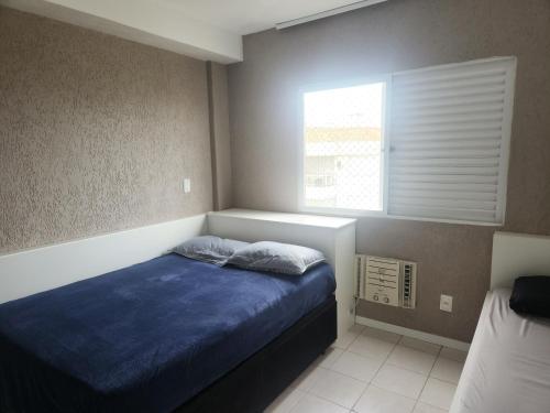 um quarto com uma cama com lençóis azuis e uma janela em Apartamento pe na areia e com vista linda em Florianópolis