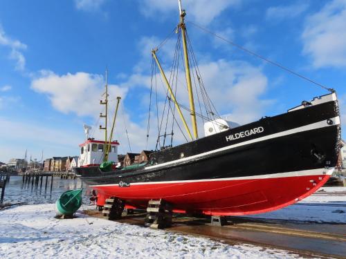 a black and red boat sitting on the sand at Ferienhaus Zur Alten Post 1 in Ockholm