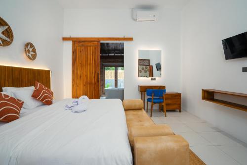 een slaapkamer met een groot wit bed en een bank bij Bali Taoka Beach Villa in Singaraja