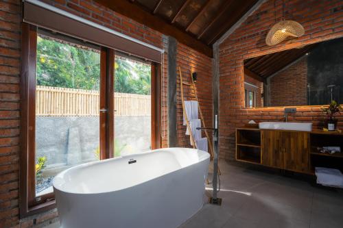 ein Badezimmer mit einer großen weißen Badewanne und einem Fenster in der Unterkunft Bali Taoka Beach Villa in Singaraja