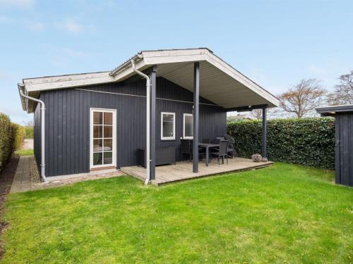 a black shed with a deck in a yard at Holiday Home Maybrit - 50m from the sea in Funen by Interhome in Assens