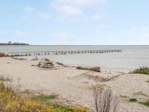 a bench on the beach with a pier in the water at Holiday Home Maybrit - 50m from the sea in Funen by Interhome in Assens